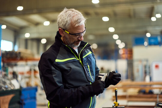 Man Using Precision Measuring Tool in an Industrial Warehouse Setting