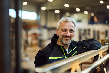Middle-Aged Man Smiling in a Comfortable Industrial Workplace Setting