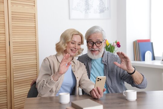 Senior man and mature woman having video chat via smartphone at home. Happy couple - Powered by Adobe