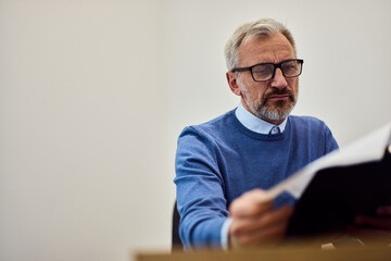 Mature Man Reading Documents in Office for Business Review