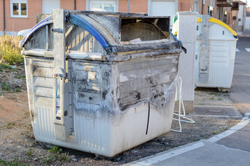Burnt and damaged recycling container on urban street