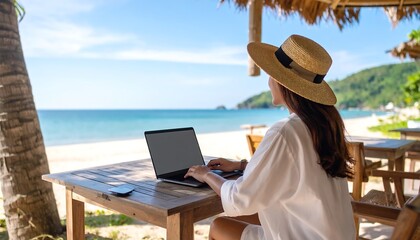 Woman working on laptop at beachside cafe