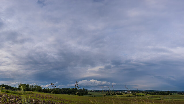 Aufnahme einer gro&szlig;en Regenwolke &uuml;ber einem Feld.