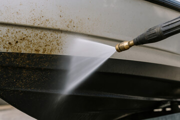 Close-up of a pressure washer cleaning the bottom of a boat.