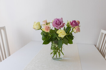 Colorful roses in a vase on a table in the interior