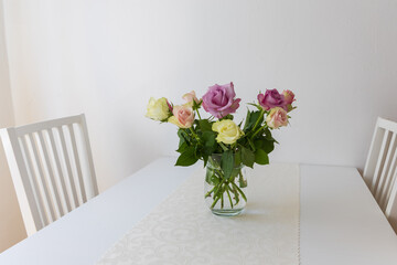 Colorful roses in a vase on a table in the interior