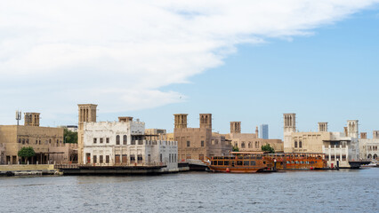 Fototapeta premium Street of Dubai old city or town or old village Al Seef Khor in Al Fahidi neighborhood, United Arab Emirates. Waterfront promenade along bank of Dubai Creek