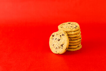 A stack of chocolate chip cookies on a red background