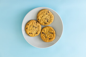 Three chocolate chip cookies on a white plate