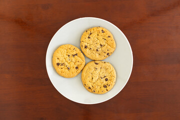 Three chocolate chip cookies on a white plate