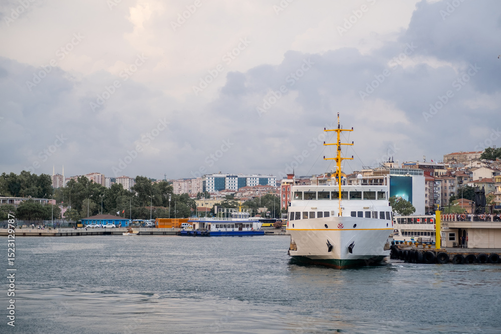 Aufkleber bosphorus ferry approaching dock with city skyline in background during cloudy day