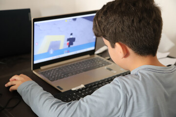 
Left-handed boy playing on a computer using the mouse with his left hand