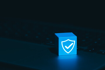 Cybersecurity and Data Protection Symbol Concept. A glowing blue cube with shield and checkmark icon on laptop keyboard, symbolizing cyber security, digital protection, trusted data security systems,