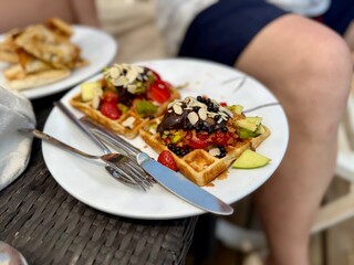 Delicious homemade waffles with whipped cream and fresh fruit. Served on a paper tray or plate. Home production plant.
