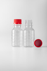 Two small plastic bottles with a red lid on a white background