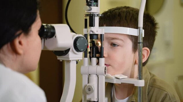 Young boy undergoing slit lamp eye exam by optometrist