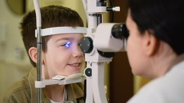 Young boy undergoing eye examination with slit lamp by optometrist