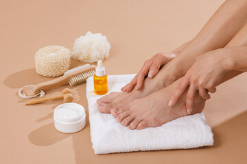 Close-up of female feet on a white towel with spa tools, oil serum, and foot cream. Concept of body...