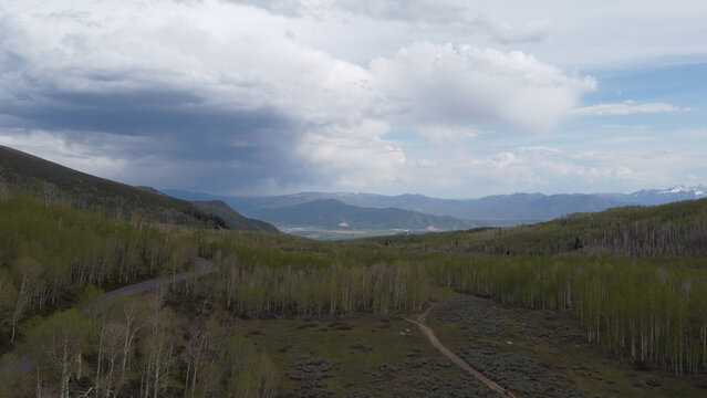 Aerial photographs of Guardsman Pass in the Wasatch Mountains of Utah, showcasing winding alpine roads, dense green forests, and high-elevation terrain under clear summer skies. Captured with a drone,