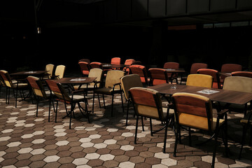 Empty colorful outdoor cafe chairs arranged on a patterned pavement in Serbia.
