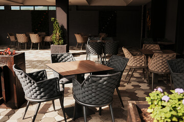 Cozy corner of outdoor terrace cafe with modern woven chairs and wooden tables in Bajina Basta, Serbia.