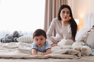 Fototapeta premium Woman suffering from postpartum depression with her little baby on bed at home. Space for text