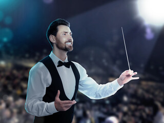Conductor directing orchestra with baton on stage of concert hall © New Africa