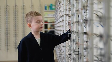 Young boy choosing eyeglasses in optical store