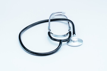 Black stethoscope resting on a white surface, representing medical care, auscultation, and the diagnosis of health conditions