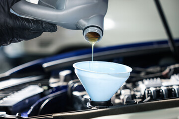 Worker pouring motor oil from canister into car engine, closeup