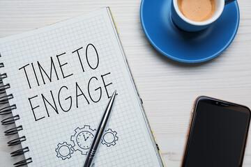 Time to engage. Words and drawing in notebook, coffee and mobile phone on white wooden table, top view