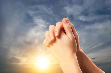 Woman praying against beautiful sky with sun, closeup