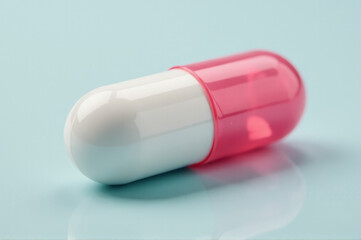 A pink and white pill sits on a table, awaiting use