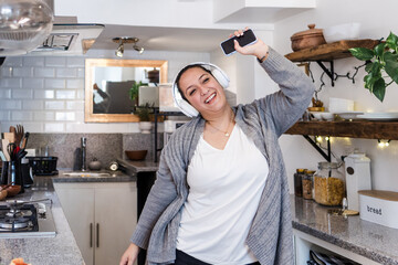 young latin woman overweight dancing and listening music using headphones and holding mobile phone...
