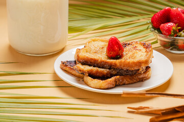 Traditional Latin American sweet bread toast with strawberry and milk, tropical setup

