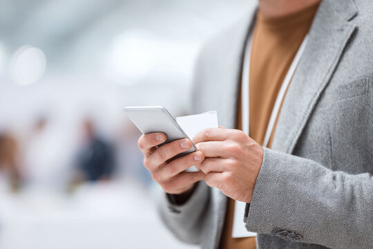 A man using his smartphone at a conference. Represents connection, communication, and networking in a modern, professional setting. Perfect for business or tech themes.