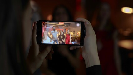Female hands holding smartphone. Lady making video on the gadget. Friends dancing in the nightclub. Lifestyle, dance, disco concept.