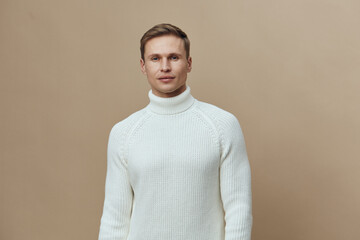 young caucasian man wear white knitted sweater look camera neutral face isolated on beige background digital detox concept