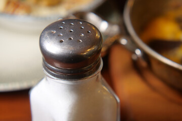 Salt shaker placed beside a delicious meal on a table