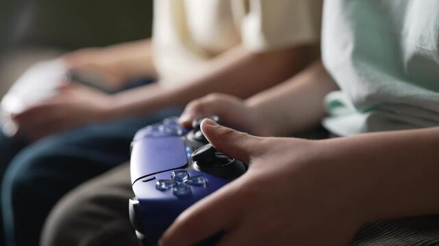 Young boys presses buttons, using joypad controller, wireless gamepad. Hobby.