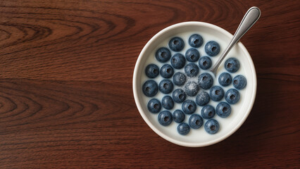 A bowl of blueberries in milk, sprinkled with sugar, arranged on a wooden table-top. Top-down photo. A light breakfast.