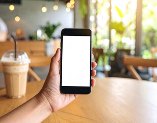 Hand casually cradles sleek black mobile phone, its blank screen reflecting warm ambiance of cozy cafe, creating sense of relaxation and modernity