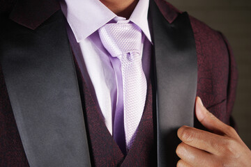 Elegant man adjusting tie at formal event indoors