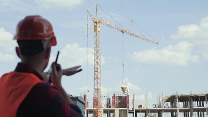 Foreman gesticulating and coordinating works over walkie-talkie on building site