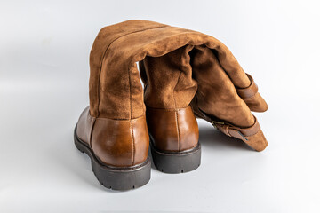 Close-up of folded brown leather and suede boots with rugged sole and elegant buckle.