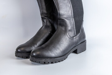Black leather knee-high boots featuring rugged sole and elegant silver buckle detail.