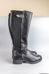 Stylish black leather knee-high boots with silver buckle and textured elastic side panel.