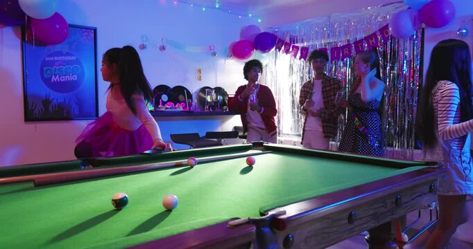 When birthday music starts, diverse friends singing karaoke and playing pool at table in rec room