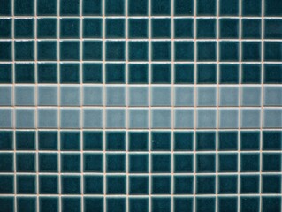Close-up of blue and teal ceramic tiles arranged in a grid pattern with a horizontal light blue strip in the middle