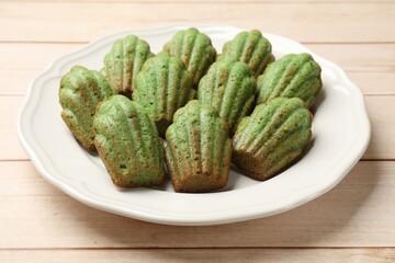 Tasty matcha madeleine cakes on light wooden table, closeup